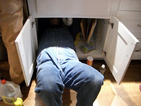 plumber fixing pipes under the sink