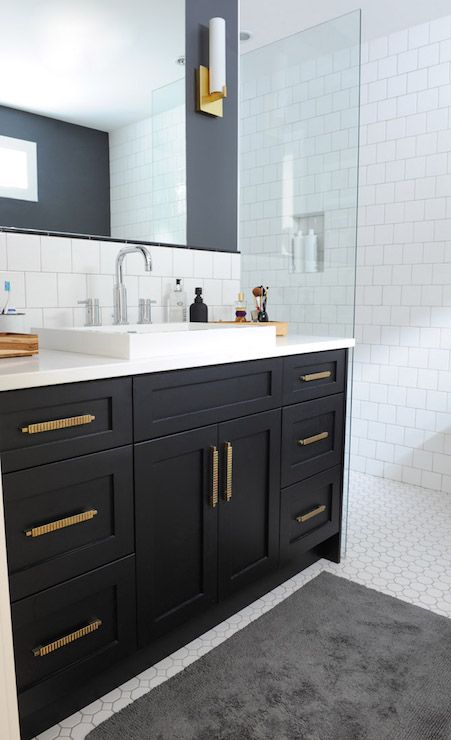 black bathroom single sink vanity with gold cabinet hardware and walk in shower